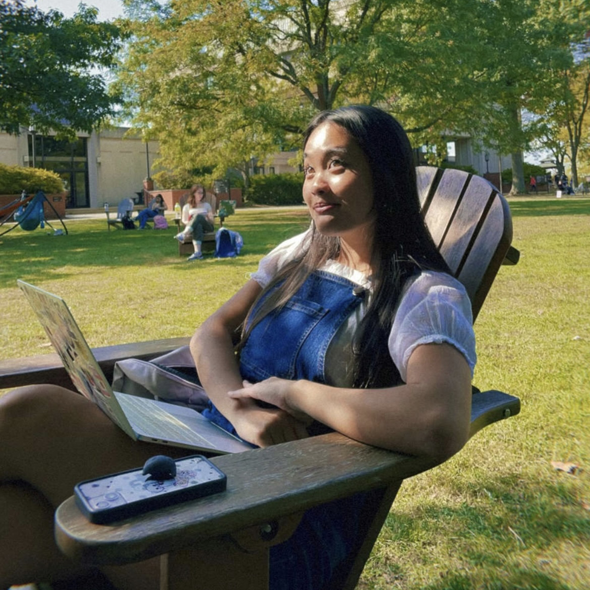 Jolie Phan sits and smiles in an Adirondack chair on Shadyside Campus's quad 