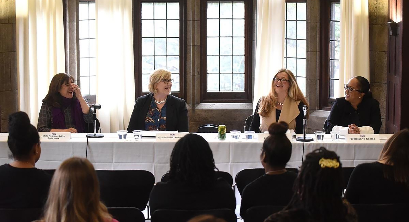 A panel of smiling and laughing women are seated at a PCWP event