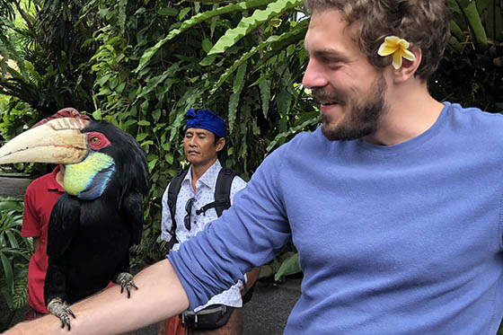 Photo of a Chatham University student in a jungle with a large exotic bird perched on her arm