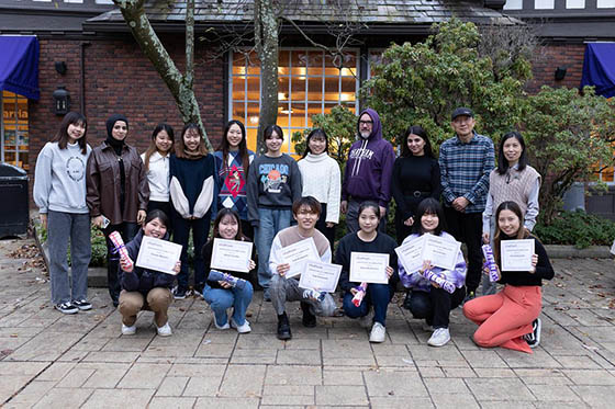Photo of a group of international students holding certificates and posing for a group picture