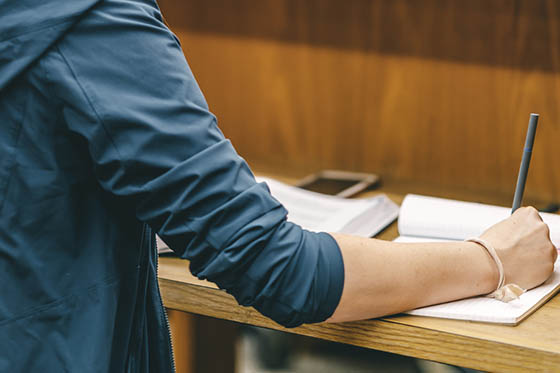 Close-up photo of a student writing in a notebook in the library