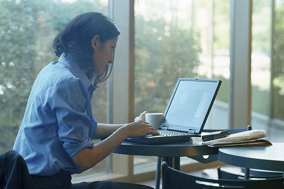 Photo of a woman in a blue shirt working on a laptop