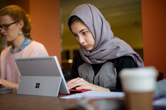 Photo of a Chatham University student in a hijab, working on a tablet in Cafe Rachel