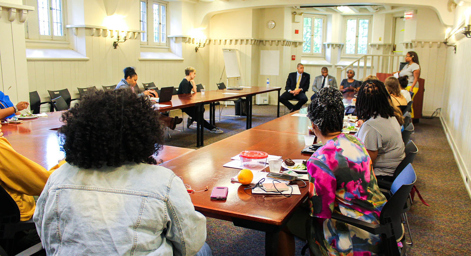 Photo of a Chatham University classroom, with students sitting around tables faced towards a panel of instructors