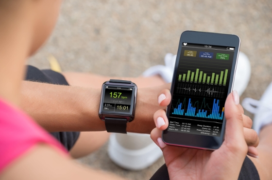 Woman compares exercise data on smart watch and smart phone. 