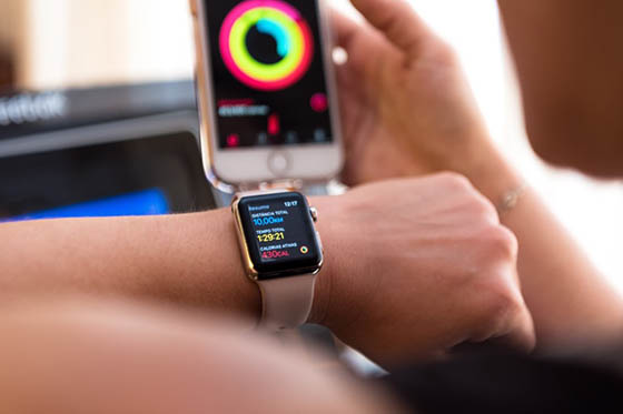 Woman compares exercise data on smart watch and smart phone.