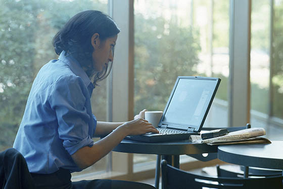 Photo of a woman sitting at a table looking at her computer