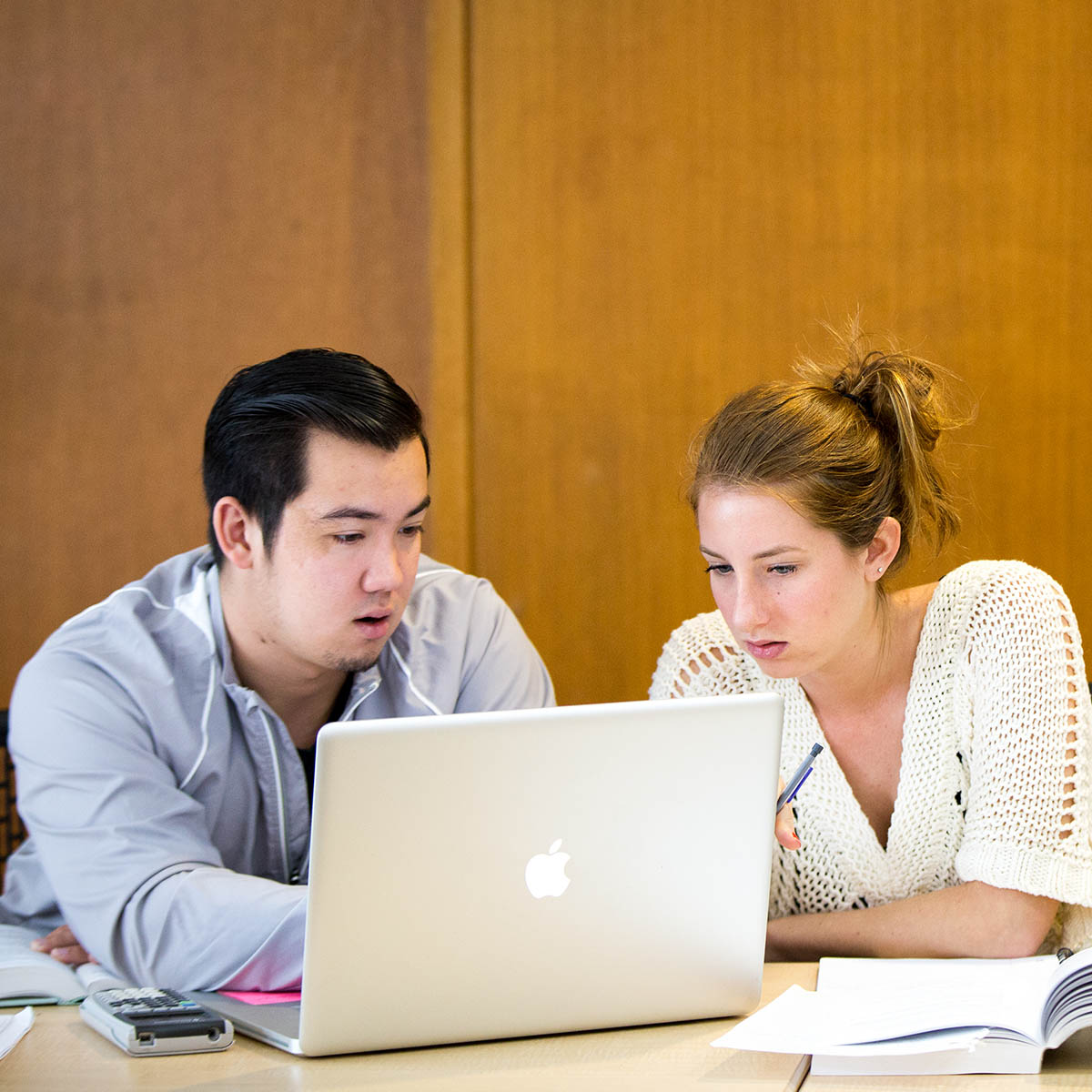 Photo of two students working together on a laptop in a classroom