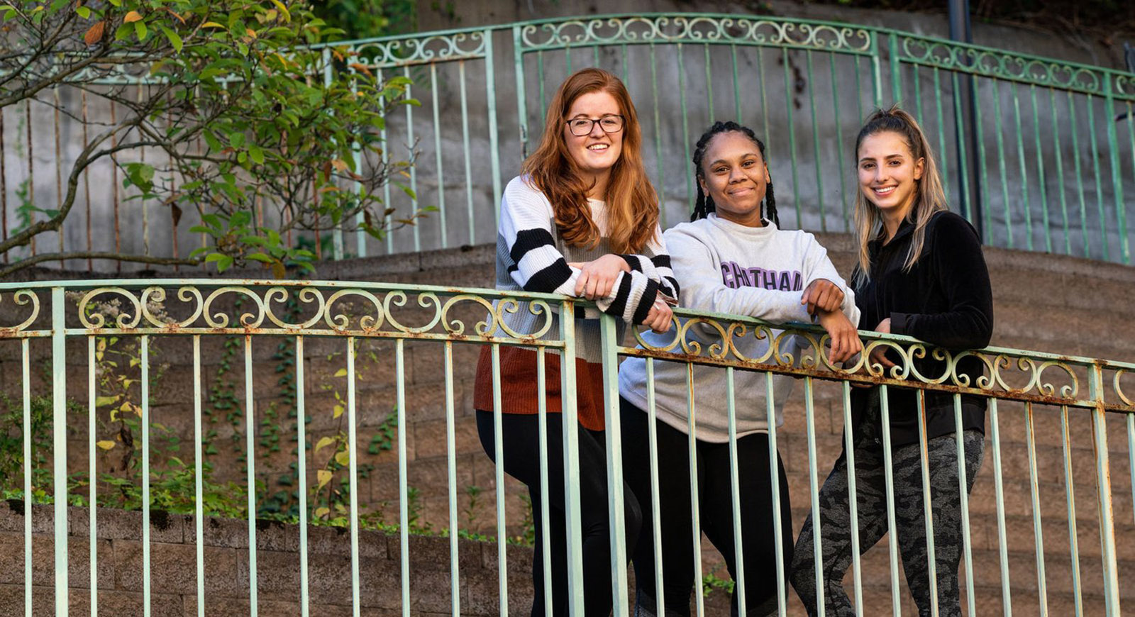 Photo of three Chatham University ELOTD students posing in front of gate