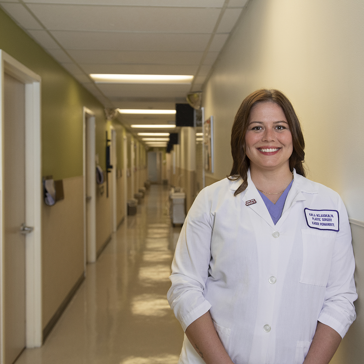 Photo of Kayla McLaughlin in a white smiling in a hospital corridor