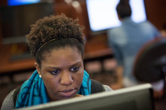 Photo of a woman working on a computer in a computer lab