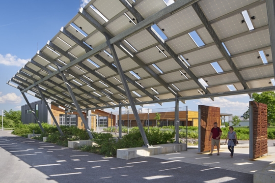 Photo of two people walking under a solar panel canopy shading their path at Chatham University's Eden Hall Campus. 