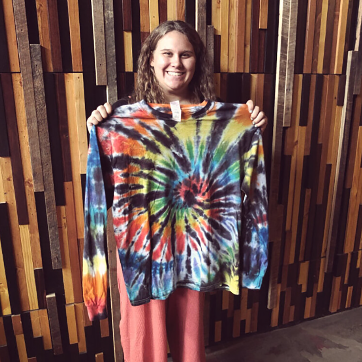 Photo of a young woman holding up a tie-dye shirt