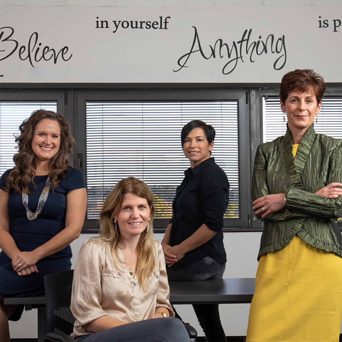 Four women in professional clothing posing for a photo in the Women's Business Center