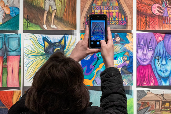 Gallery visitor takes a photo of colorful art on the wall