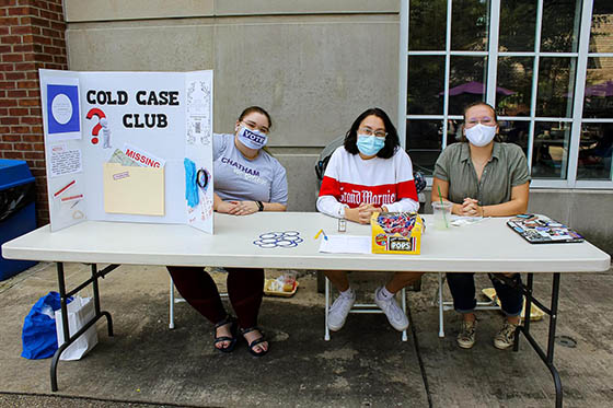 Photo of a woman working on her laptop with a Chatham University sticker in a lecture hall