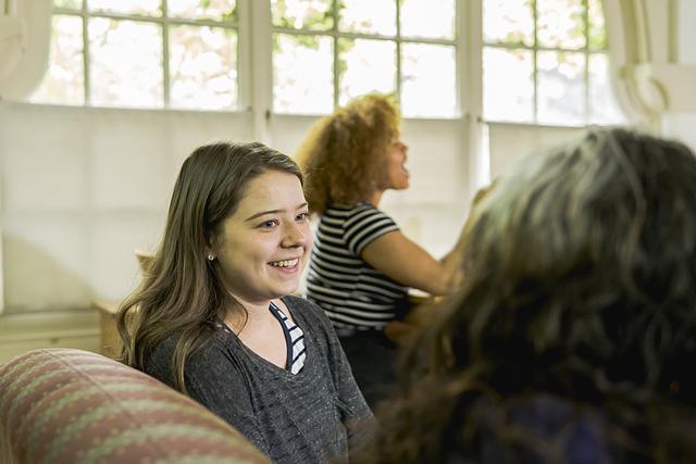 Smiling students are seated together in a residence hall lounge, laughing and talking