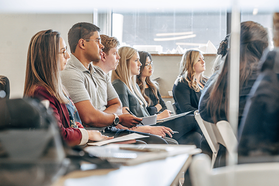 Photo of Chatham University students sitting at desks in a classroom listening to a lecture.