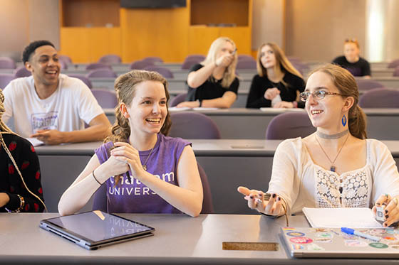 Photo of Chatham University students sitting in wooden cubicles, studying between stacks of books in Jennie Mellon King Library.