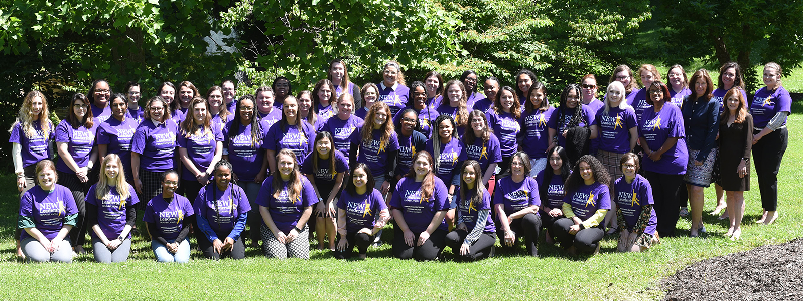 Photo of a large group of Chatham University students wearing purple New Leadership Program T-shirts, posing together outside on grass. 