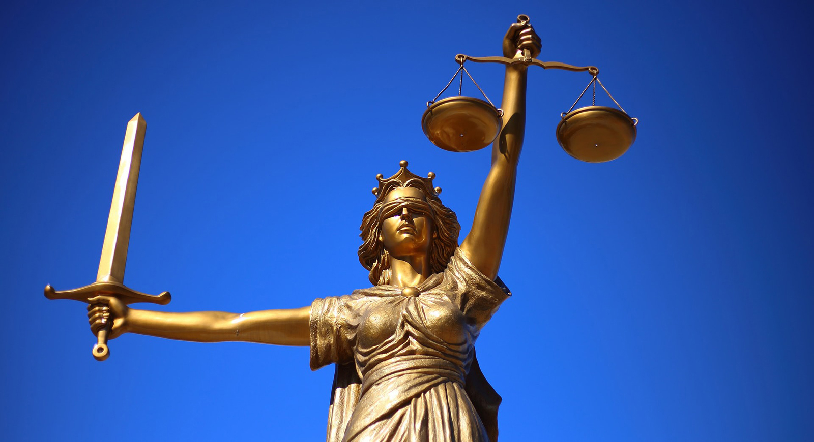 Photo of a gold statue of Justice, a blindfolded woman holding a sword and law scale. 