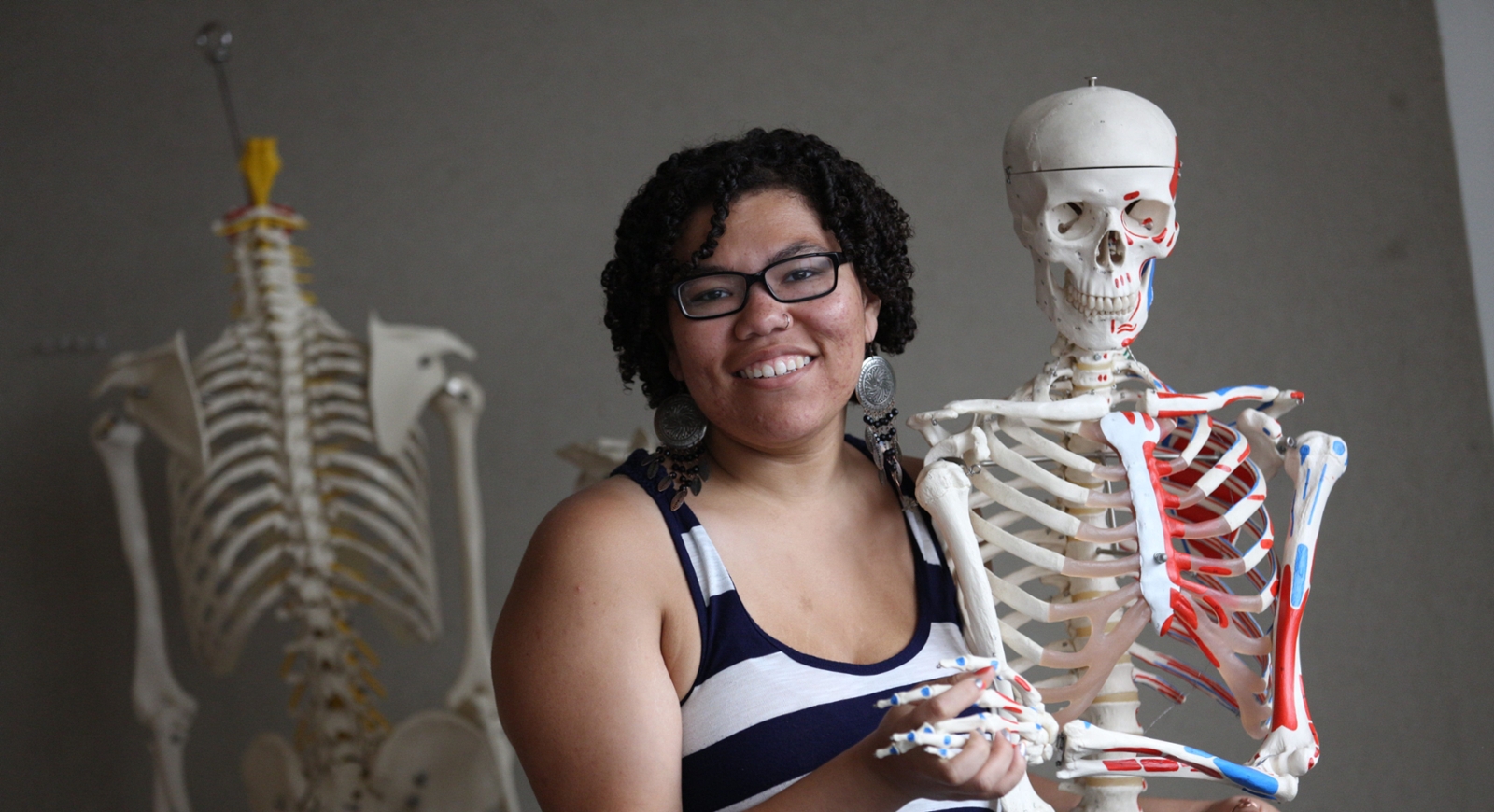 Photo of a smiling Chatham University student holding a fake skeleton