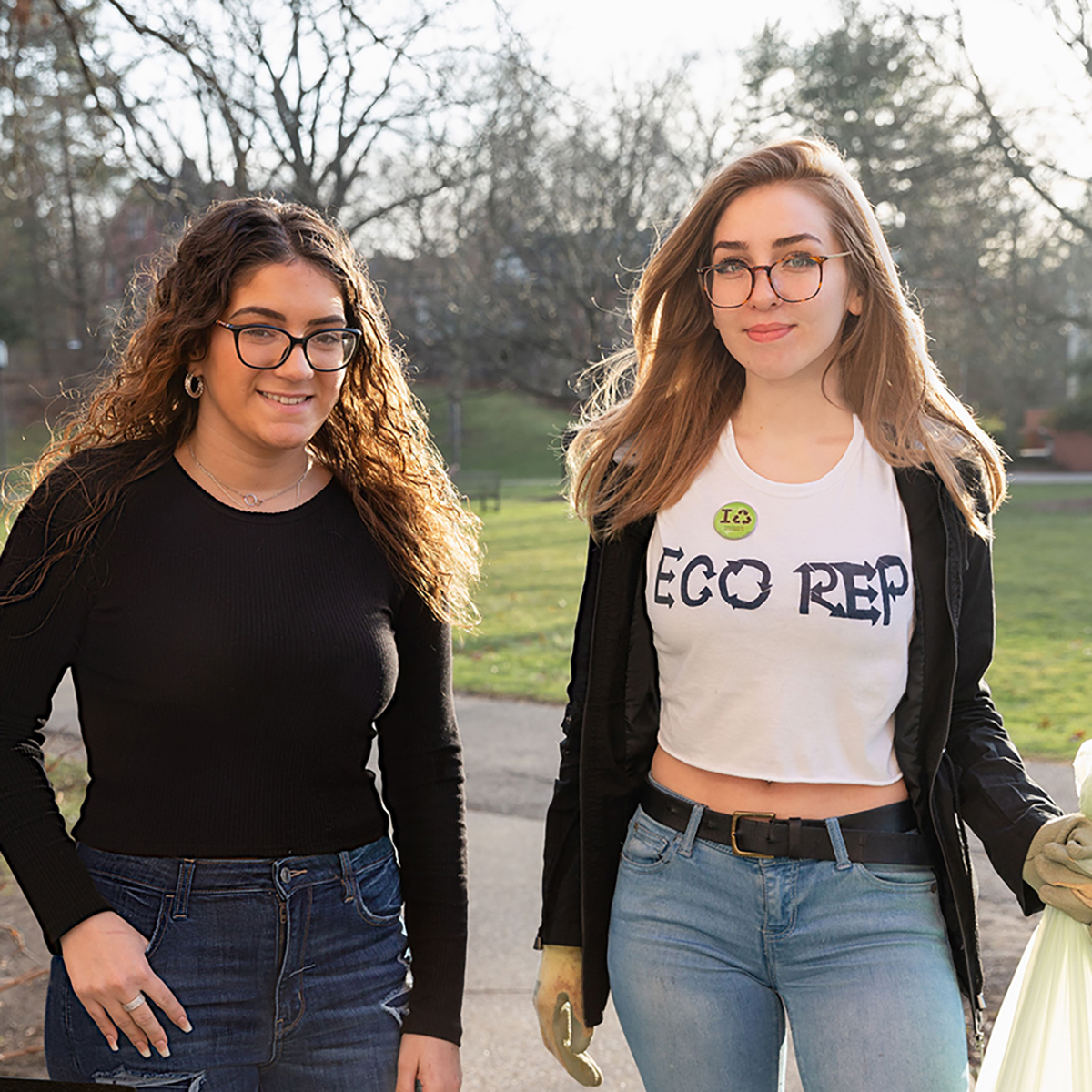 Photo of two students, one wearing an Eco Rep shirt, pick up litter on Shadyside Campus