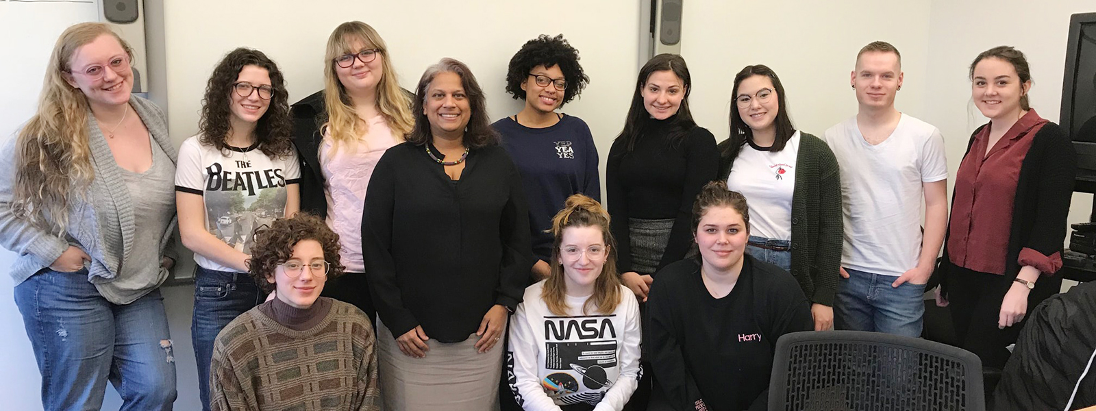 Photo of a group of students and instructor posing together at the front of a classroom