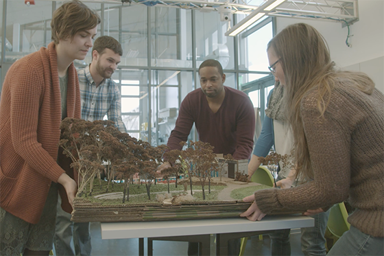 Photo of four Chatham University students in a lab on Eden Hall Campus, working on a model of a forest