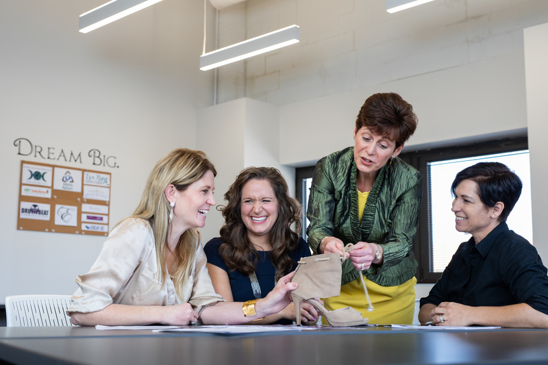 Photo of four women laughing and talking together around a table.