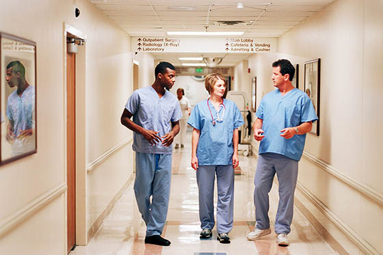 Photo of three nurses walking and talking in a hospital hallway