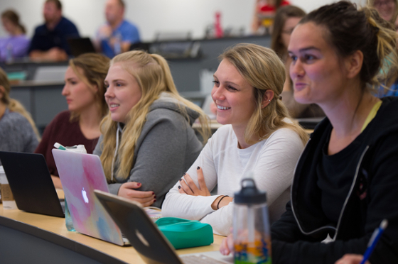 Photo of smiling Chatham University students paying attention to a lecture