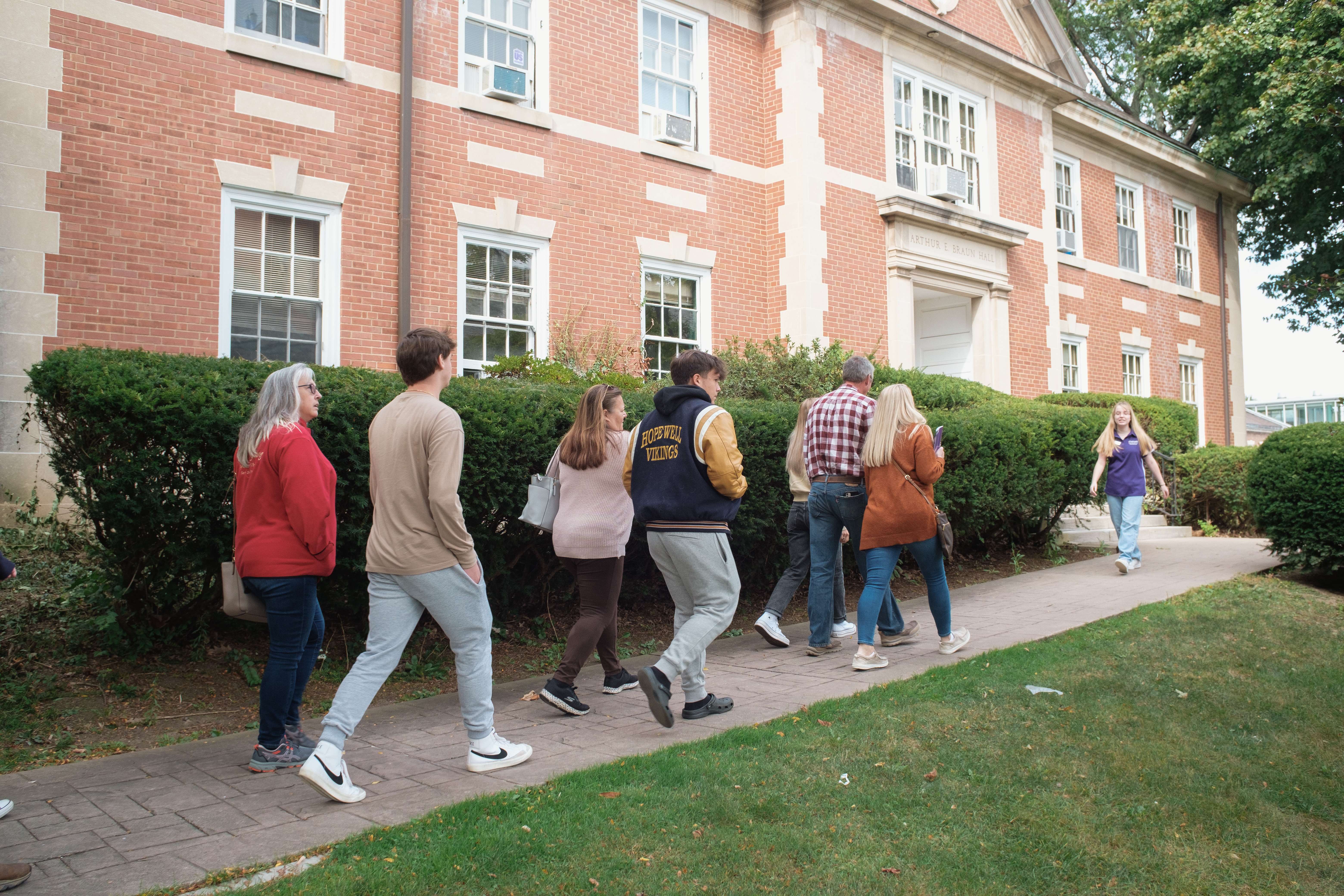 Photo of a student in a Chatham University sweatshirt, working at a laptop in a lecture hall and taking notes