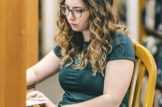 Photo of a student writing at a library table