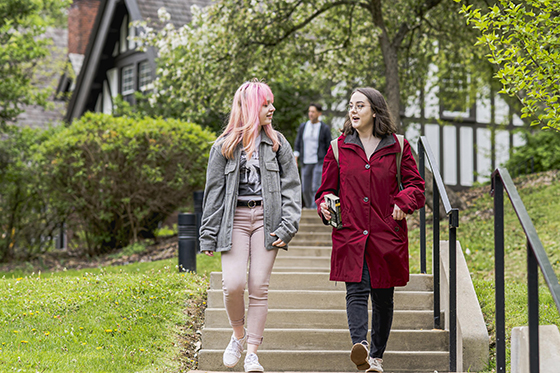 Photo of two Chatham University students walking across the Shadyside Campus, talking and walking down stairs