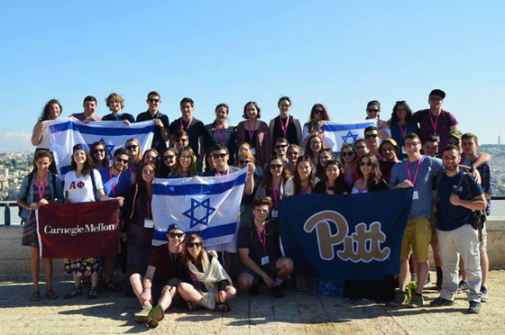 Photo of a group of Jewish students posing with Israel, Carnegie Mellon University, and University of Pittsburgh flags while on Birthright