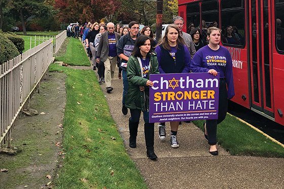 Photo of a long line of Chatham University community members marching with signs reading Chatham is Stronger Than Hate