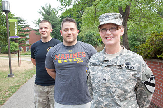 Photo of three military members, one in uniform, pose on Shadyside Campus