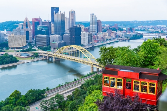 Photo of the Pittsburgh skyline featuring Mount Washington and a red incline car. 