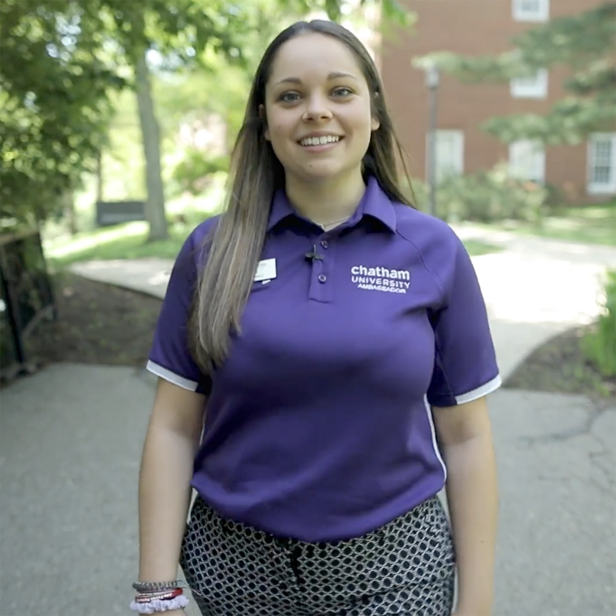 Photo of a Chatham University student in a bright purple polo shirt, smiling