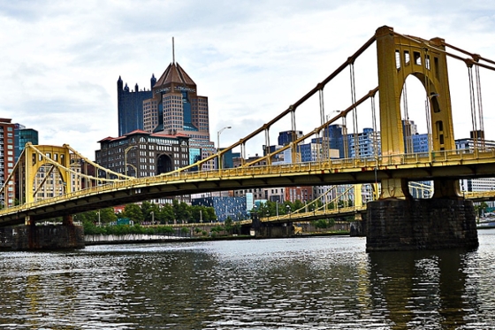 Photo of a yellow bridge in front of the Pittsburgh skyline