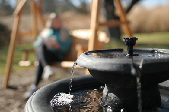 Photo of Chatham's sensory garden, with a fountain in the foreground and a person on a bench in the background