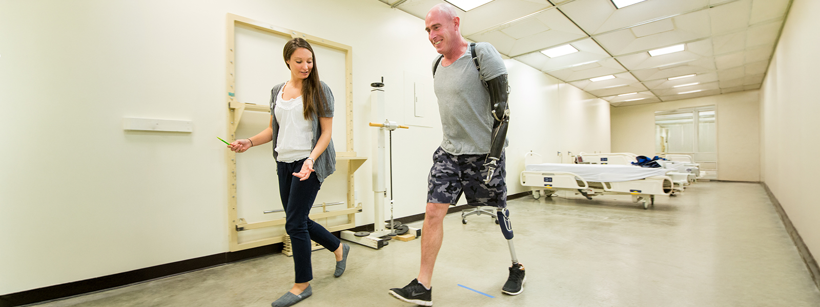 Physical Therapy student walking with an amputee in hospital