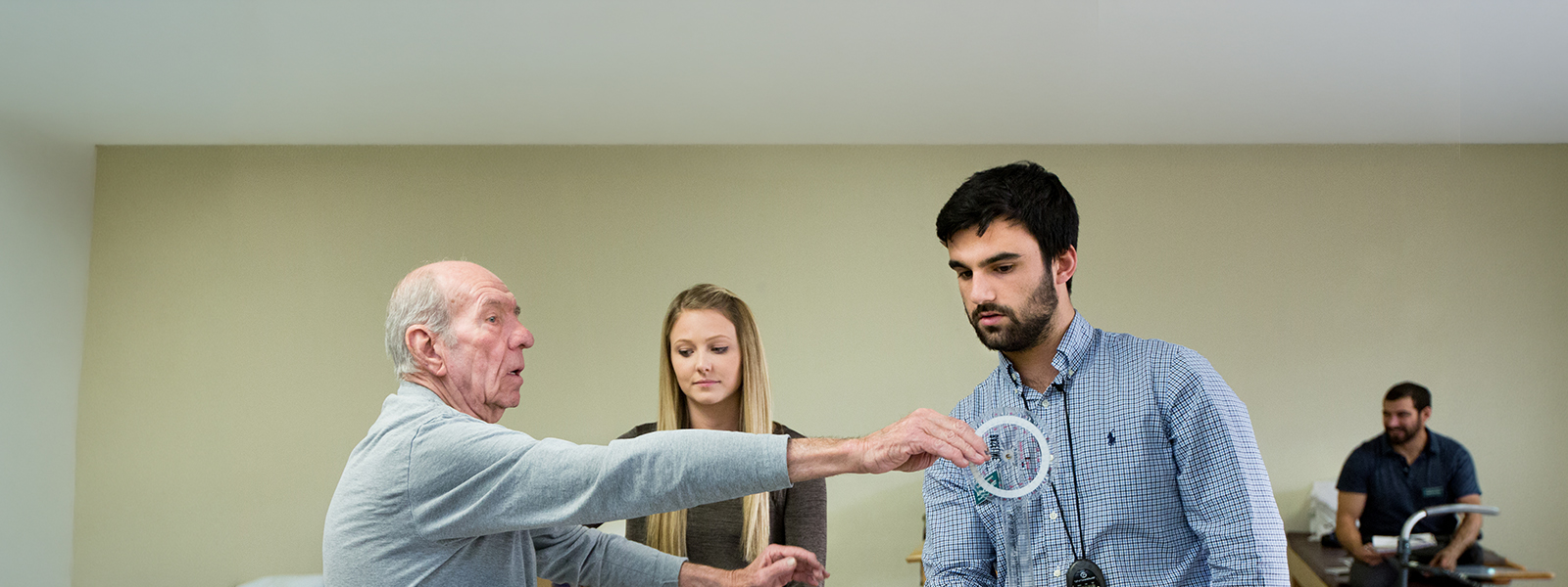 Two physical therapy doctorate students working with an elderly man