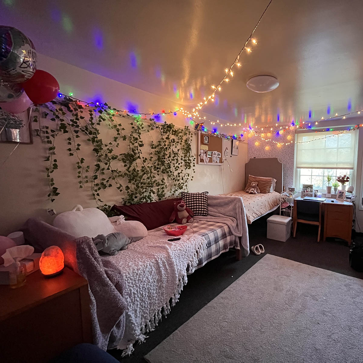 Photo of a decorated dorm room with cozy pillows and blankets and fairy lights