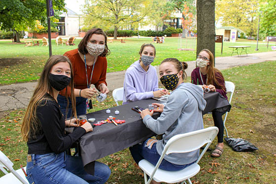 Photo of five masked students painting pumpkins outside in the Shadyside Campus quad
