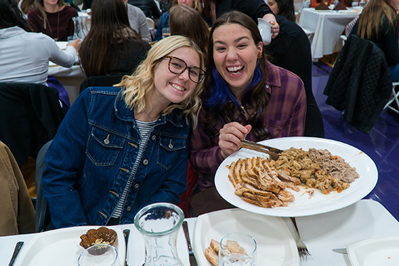 Photo of Chatham University students at Harvest Dinner holding a plate of turkey and stuffing. 